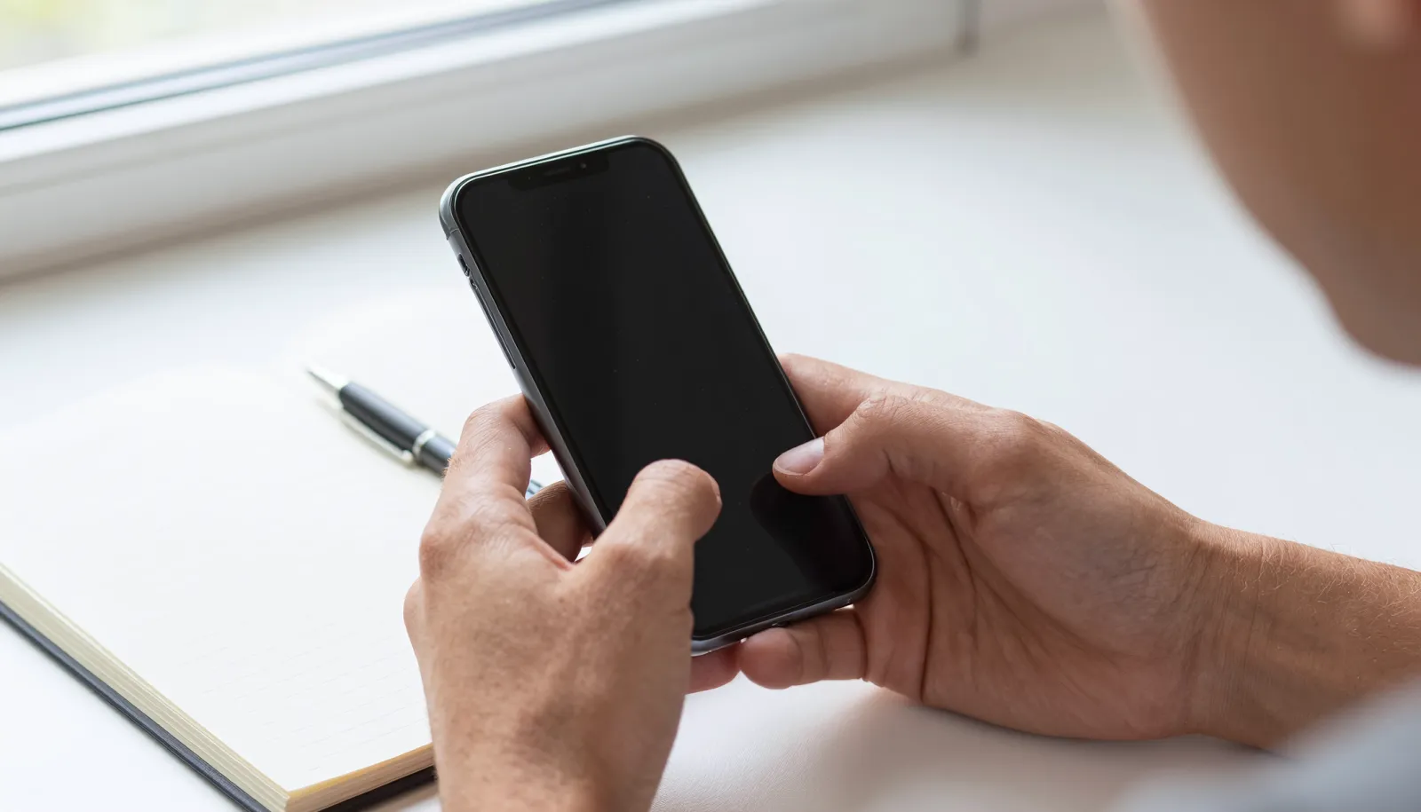 Hender holder mobiltelefon – klar til å bestille billig mobilabonnement