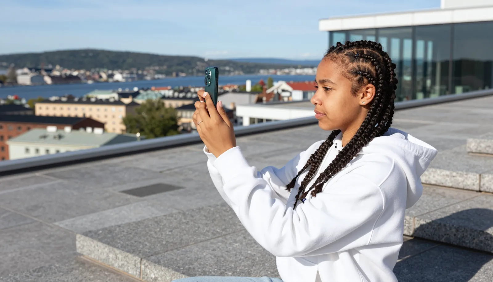 iPhone med abonnement – ung kvinne tar bilde med ny mobil på Operataket i Oslo